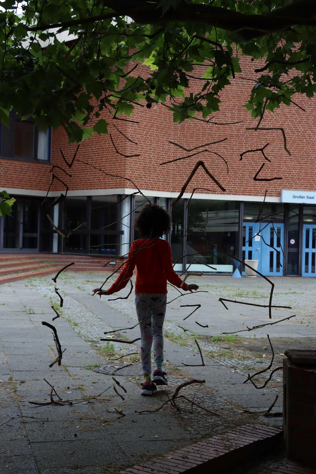 Land-Art im Sommerferienkurs mit Alice Baillaud: Ein geheimes Portal aus geschnitzten Ästen im Hof des Gemeinschaftshauses Gropiusstadt